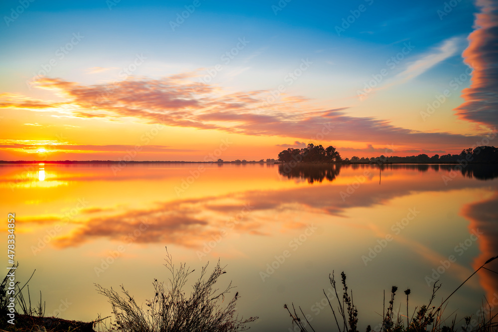 Obraz premium Gorgeous panorama on the lake at sunset with the reflection of the clouds on the water, vivid colors