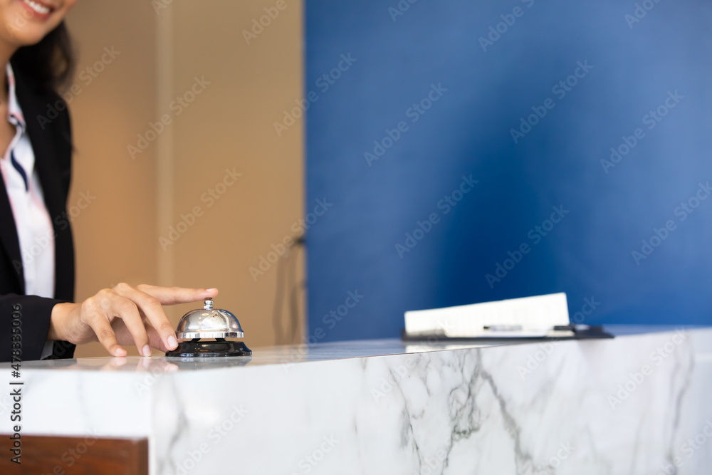 Ring bell call service with hand on hotel reception desk