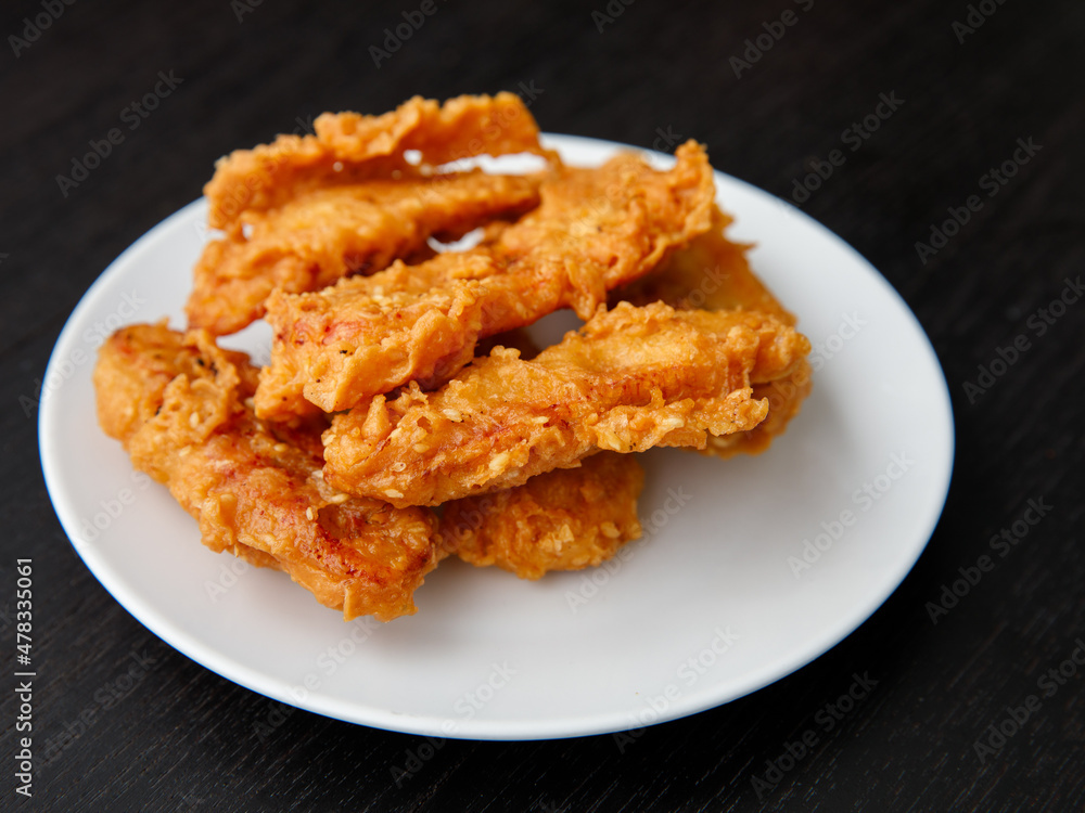 deep-fried fritters sliced banana, also known as Kluay khek, served on white plate on black wooden table.