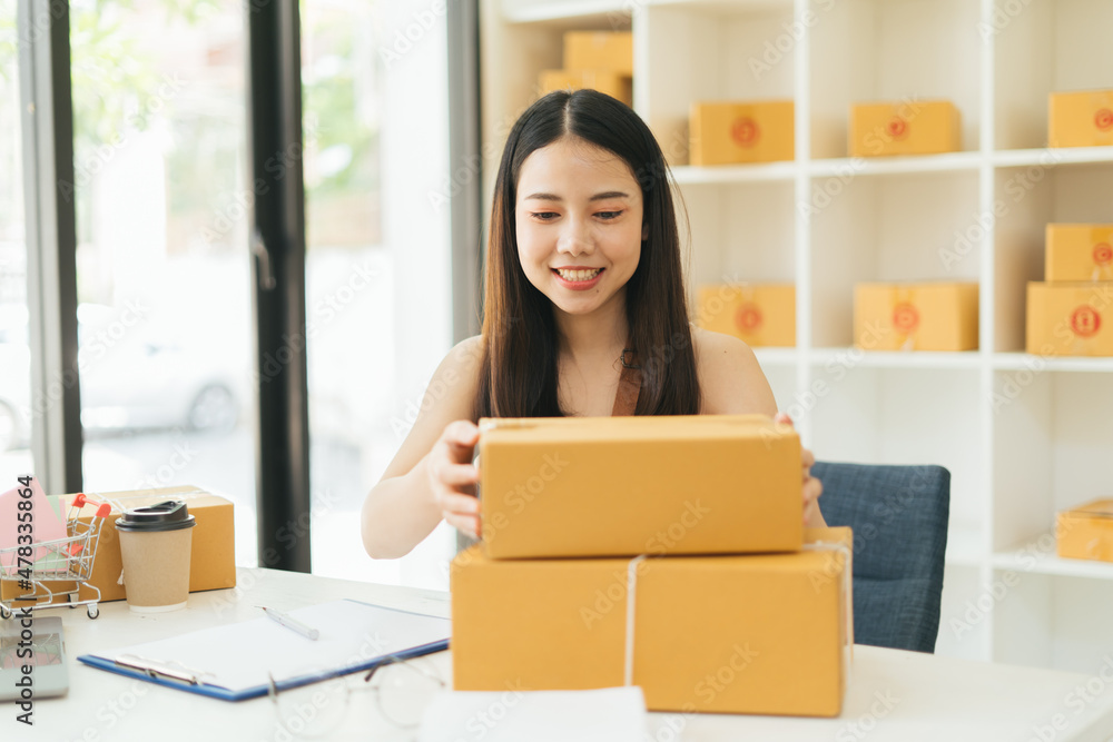 Young Asian small business owner happy with his ecommerce business preparing parcel for her online orders Young Asian small business owner happy with his ecommerce business preparing parcel for her online orders