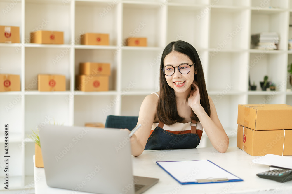 Young Asian small business owner happy with his ecommerce business preparing parcel for her online orders Young Asian small business owner happy with his ecommerce business preparing parcel for her online orders