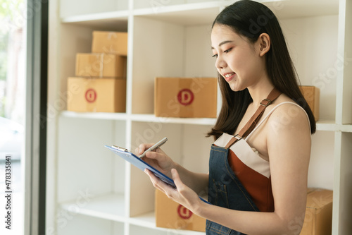 Young woman freelancer working and checklist and writing order with cardboard box ,SME business online and delivery concept