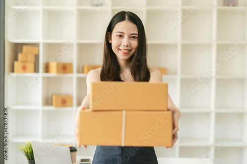 Young Asian small business owner happy with his ecommerce business preparing parcel for her online orders