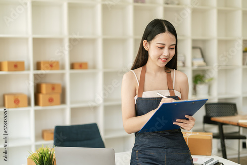 Young woman freelancer working and checklist and writing order with cardboard box ,SME business online and delivery concept