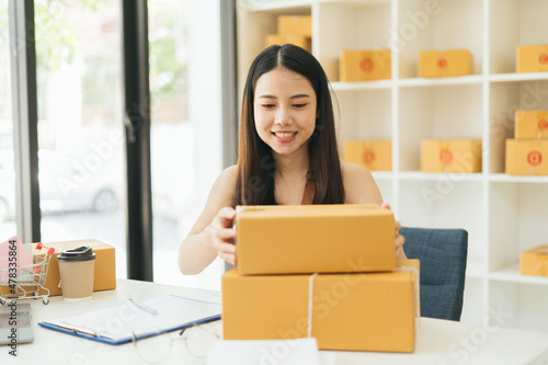 Young Asian small business owner happy with his ecommerce business preparing parcel for her online orders