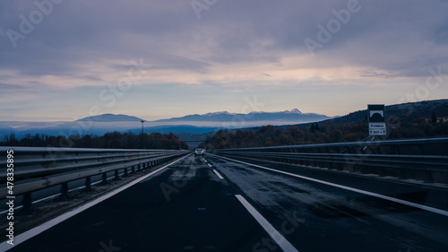 Highway at dawn car travels the road to the snow-capped mountains cold temperature  free road with no traffic