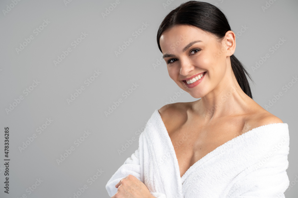 Portrait of young caucasian woman with beauty face and healthy hydrated facial skin standing in bathrobe with naked shoulder isolated on copy space background. Cosmetology, dermatology concept Portrait of young caucasian woman with beauty face and healthy hydrated facial skin standing in bathrobe with naked shoulder isolated on copy space background. Cosmetology, dermatology concept