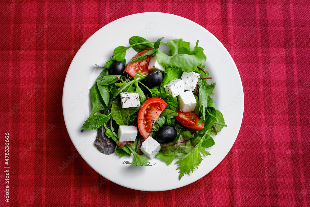 Fresh Greek salad in white plate on red background. closeup and top view. Fresh Greek salad in white plate on red background. closeup and top view.