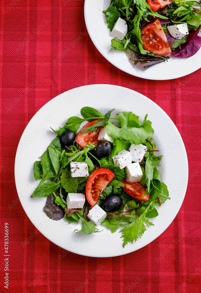 Fresh Greek salad in white plate on red background. closeup and top view.