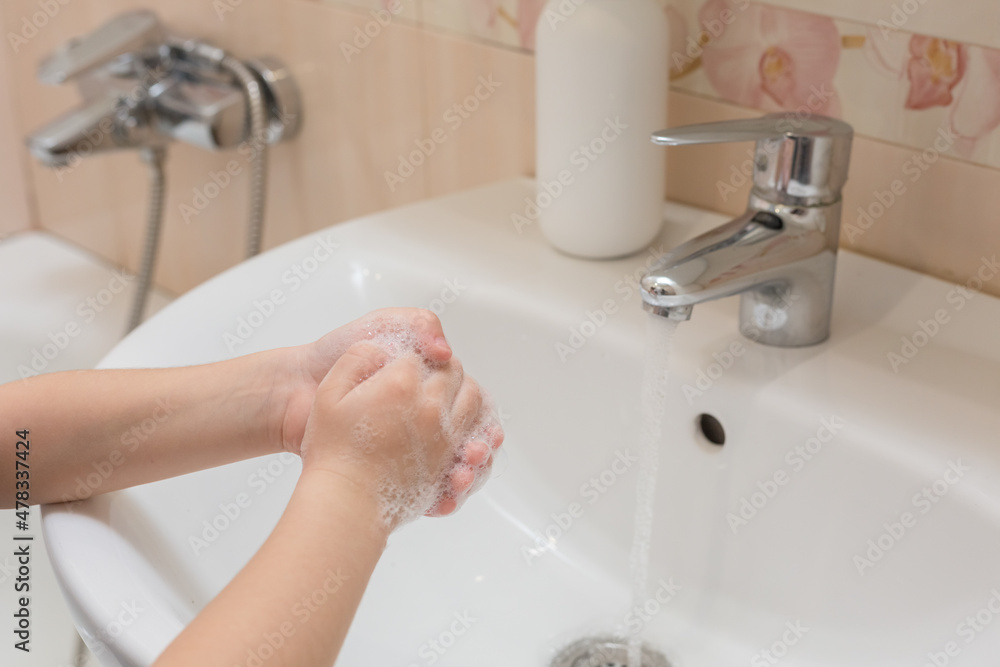 The hands of a little boy washing his hands with soap and water in the bathroom. Cleanliness and hygiene. The hands of a little boy washing his hands with soap and water in the bathroom. Cleanliness and hygiene.