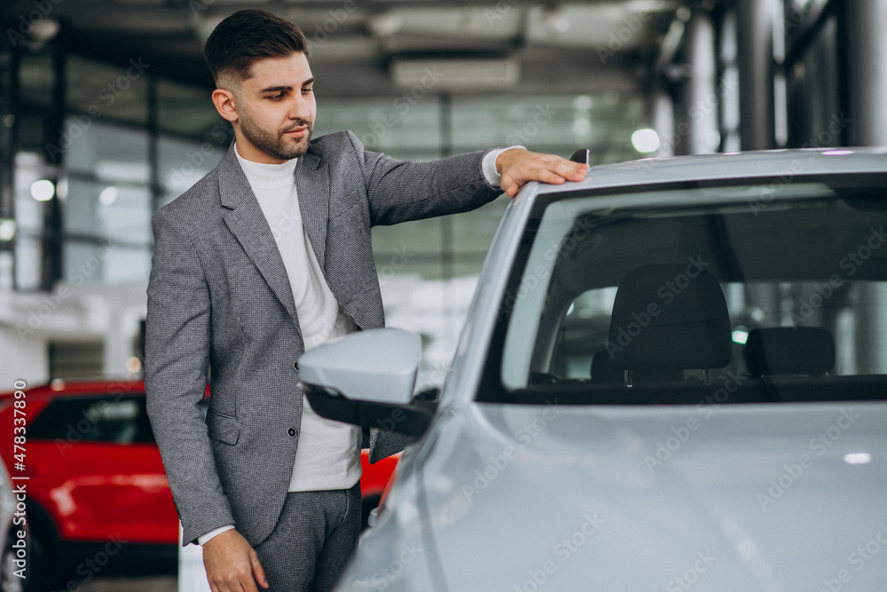 Handsome business man choosing a car in a car showroom Handsome business man choosing a car in a car showroom