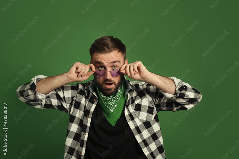 Fashionable young man in stylish outfit with bandana on green background Fashionable young man in stylish outfit with bandana on green background