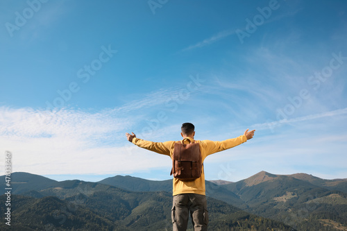 Canvas-taulu Tourist in mountains on sunny day, back view