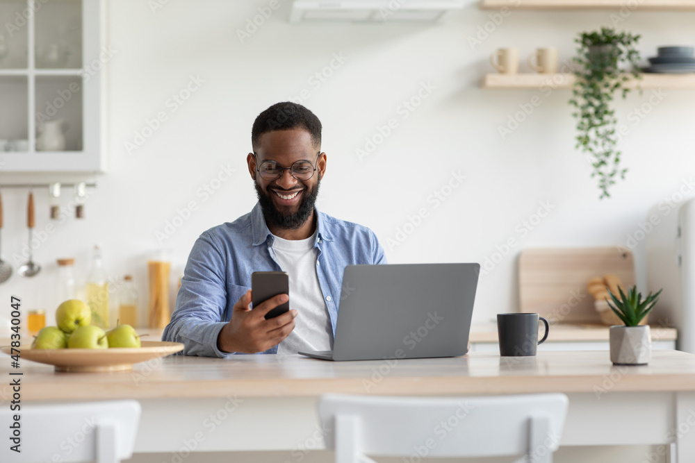Smiling glad young african american with beard businessman in glasses checks mail on smartphone Smiling glad young african american with beard businessman in glasses checks mail on smartphone