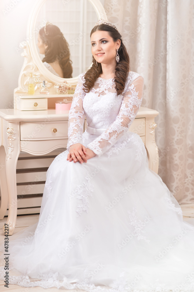 Portrait of young beautiful bride in white dress posing