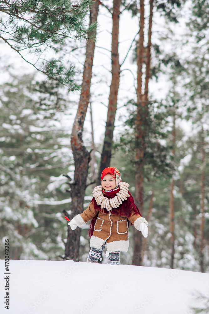 Child girl walks with lollipop in hand and bagels bunch on her neck in snowy forest. Child girl walks with lollipop in hand and bagels bunch on her neck in snowy forest.