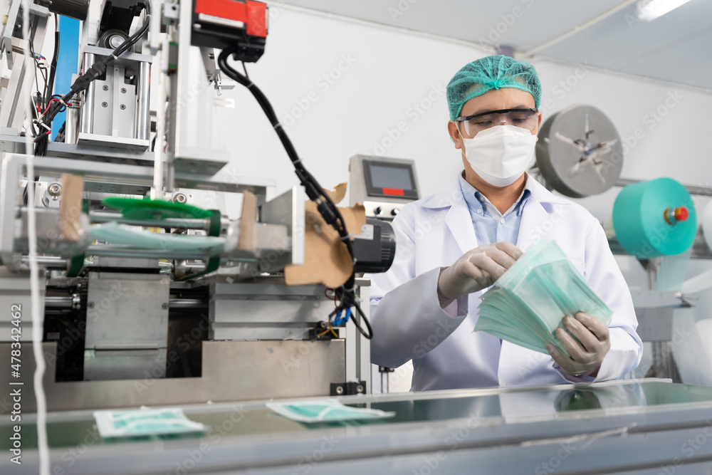 male factory worker are producing medical face masks, counting and checking of quality from machine male factory worker are producing medical face masks, counting and checking of quality from machine