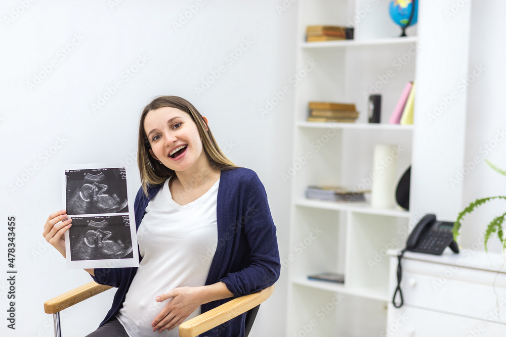 Photo of smiling pregnant woman with ultrasound result.