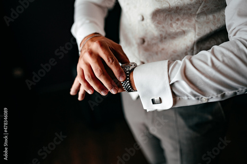 Ein festlich gekleideter Mann schaut auf seine Uhr