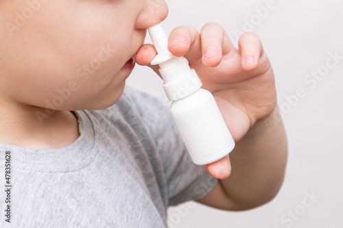 Cropped shot of a caucasian child using nasal spray for a runny nose or congestion isolated on a white background. Treatment of the disease. Rhinitis, sinusitis, flu, cold. Dependence on drops