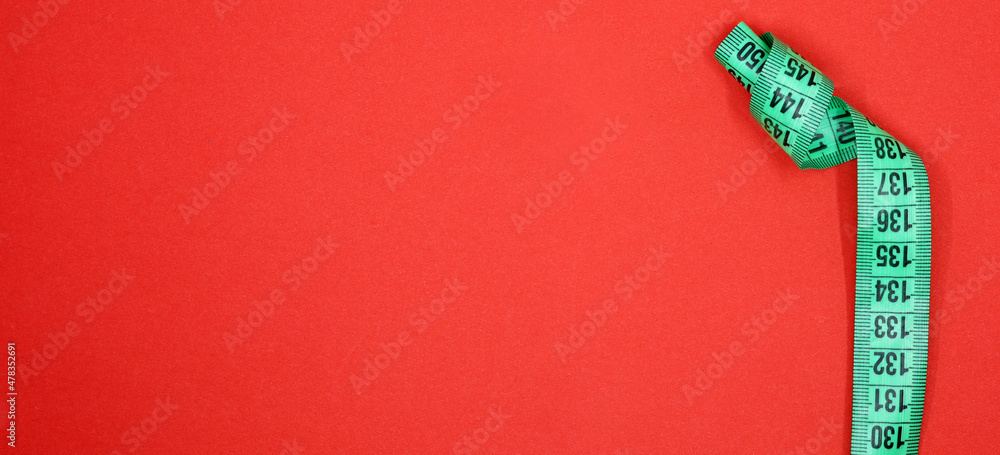 Fototapeta premium green tape measure on red background