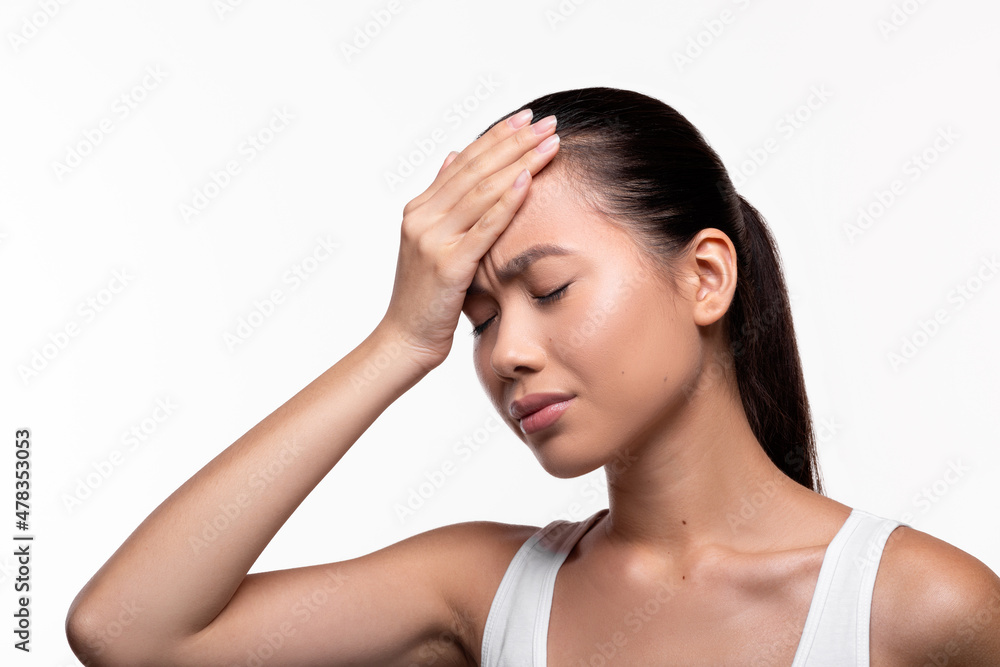 Unhappy millennial chinese lady touching her forehead Unhappy millennial chinese lady touching her forehead