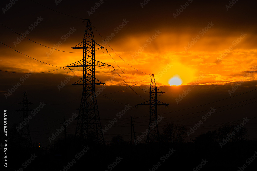 Fototapeta premium High voltage power line at sunset. Silhouettes of the metal pillars