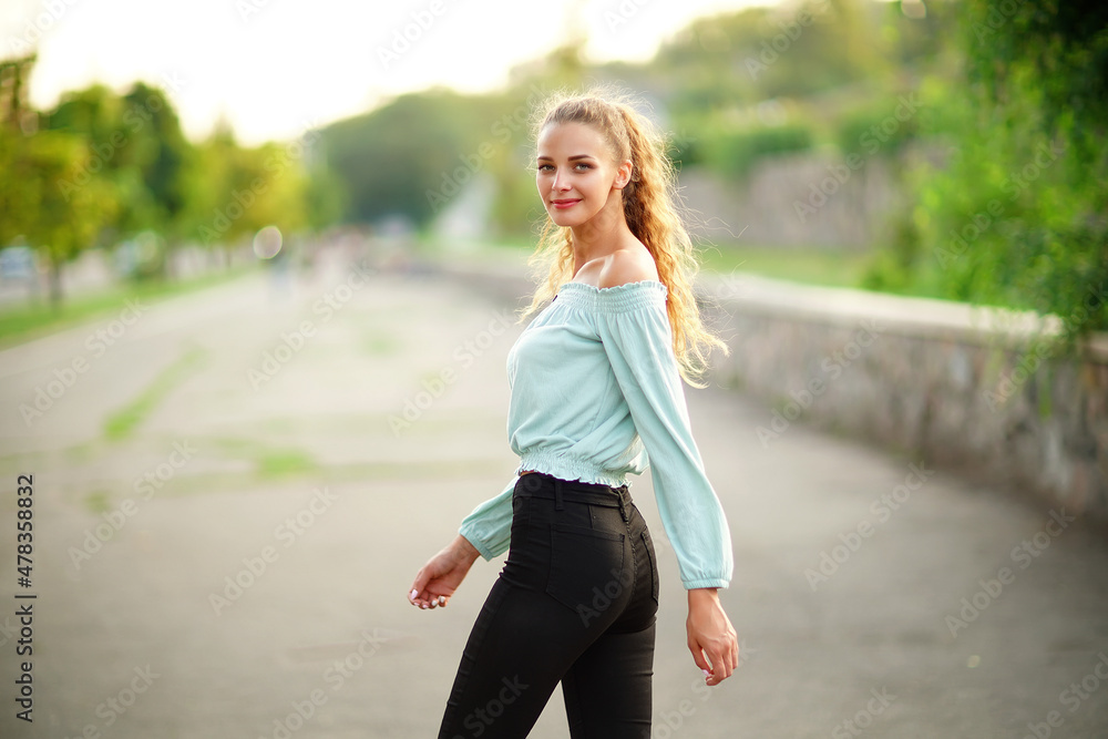 Back view of stylish beautiful girl who posing while wears in summer bright clothes in the park Back view of stylish beautiful girl who posing while wears in summer bright clothes in the park