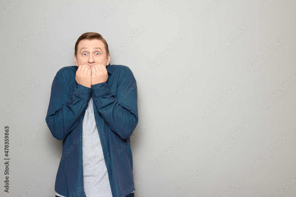 Portrait of shocked frightened blond mature man biting his nails Portrait of shocked frightened blond mature man biting his nails
