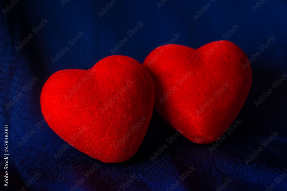 Fototapeta premium Two red corduroy hearts on a dark blue background. The concept of love, relationship, engagement, wedding.