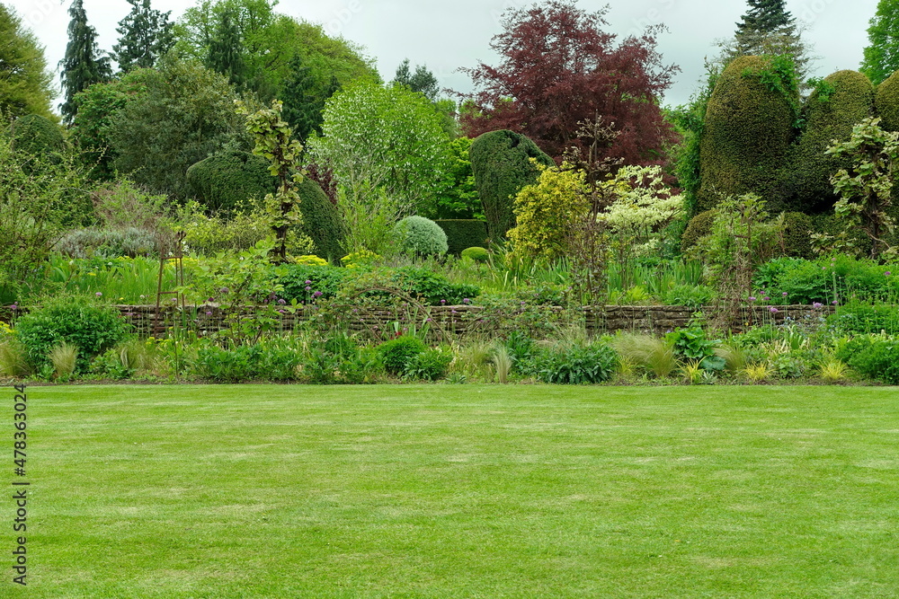 Obraz premium Scenic view of a beautiful English style landscape garden with a green mowed lawn and colourful flower bed