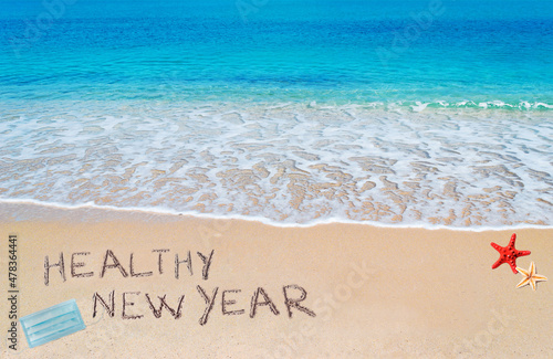healthy new year written on the sand