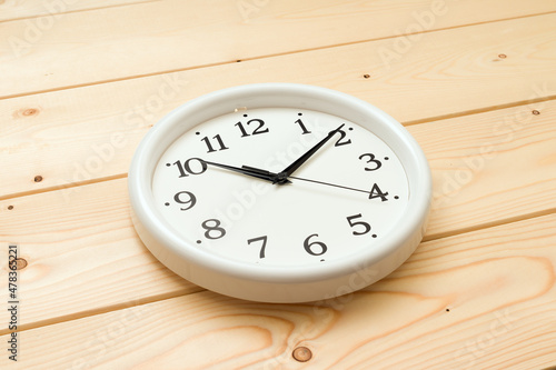 round wall clock lie on a wooden background