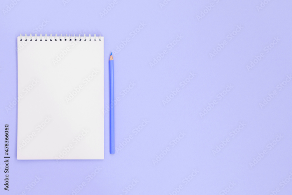 Blue pencil near a notebook, on a viloet background. There is room for text, copy space. Blue pencil near a notebook, on a viloet background. There is room for text, copy space.