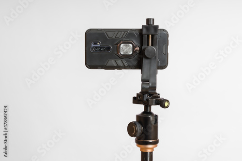 smartphone fixed on a tripod in a horizontal position on a white background, close-up