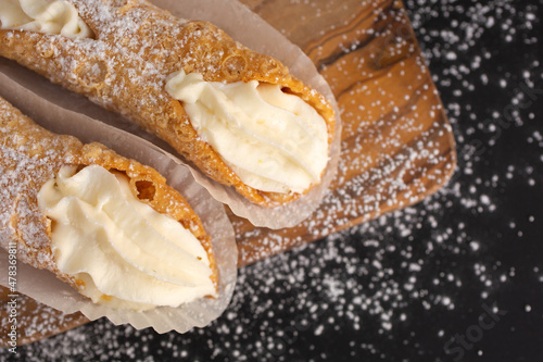 Top view of two delicious cannoli on black background