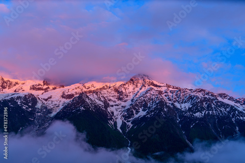 The Mont Blanc Massif surrounded by pinkish clouds in Europe, France, the Alps, towards Chamonix, in summer.