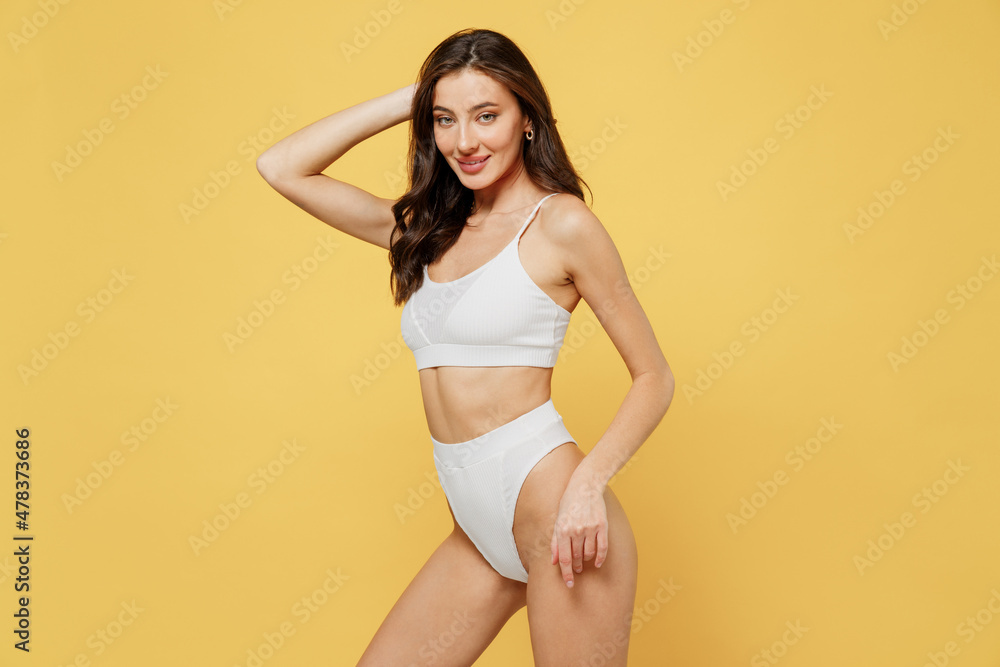 Smiling stunning caucasian sexy lovely attractive young brunette woman 20s in white underwear with perfect fit body standing posing look camera isolated on plain yellow background studio portrait Smiling stunning caucasian sexy lovely attractive young brunette woman 20s in white underwear with perfect fit body standing posing look camera isolated on plain yellow background studio portrait