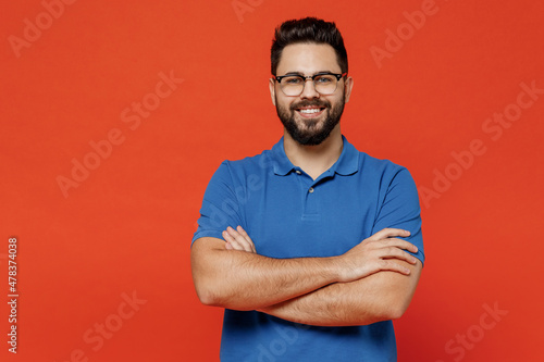 Young smiling happy attractive confident cheerful caucasian man 20s wear basic blue t-shirt eyeglasses looking camera isolated on plain orange background studio portrait. People lifestyle concept