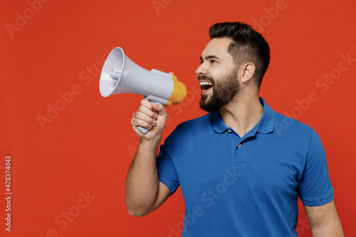 Young smiling happy caucasian man 20s wear basic blue t-shirt hold scream in megaphone announces discounts sale Hurry up isolated on plain orange background studio portrait. People lifestyle concept.