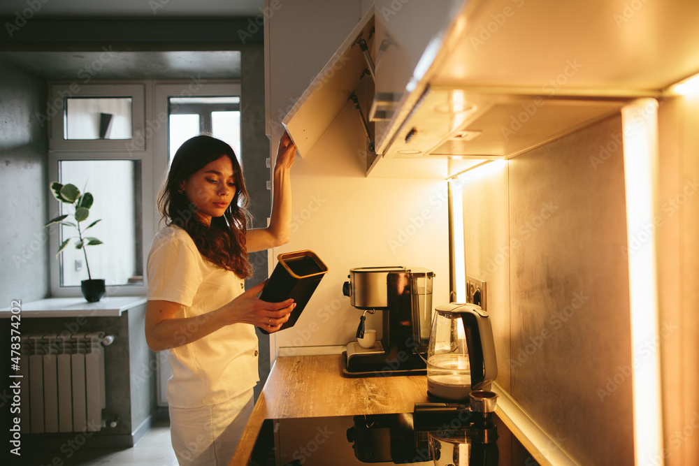 Young woman making morning coffee in the kitchen. Young woman making morning coffee in the kitchen.