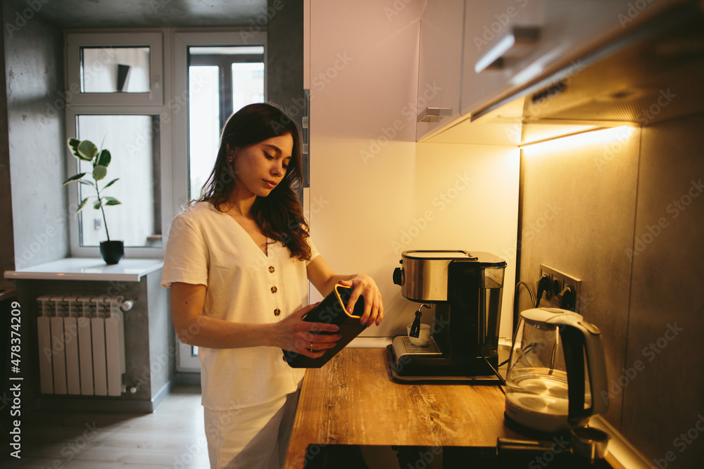 Young woman making morning coffee in the kitchen. Young woman making morning coffee in the kitchen.