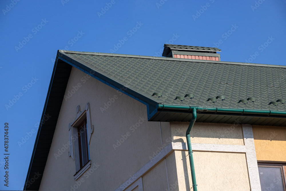 The roof of the house is made of red metal tiles, a beautiful large chimney