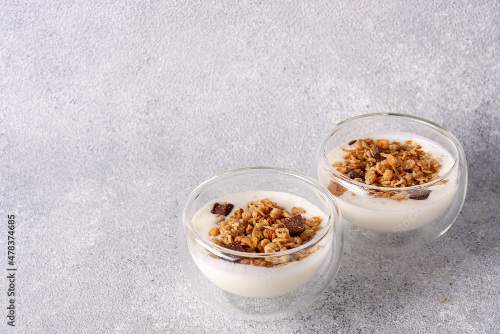 Fototapeta premium two glass cups with muesli, yogurt, chocolate on a gray background