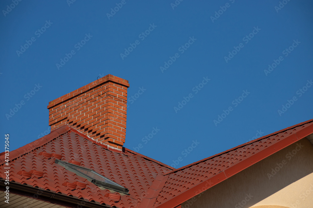 The roof of the house is made of red metal tiles, a beautiful large chimney The roof of the house is made of red metal tiles, a beautiful large chimney