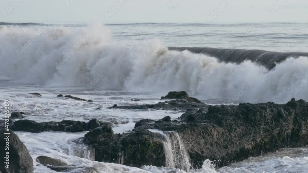 A wonderful evening seascape with a big wave crashing on a dark stone reef. Huge ocean waves break on dark rocks during a storm. Cloudy sky and golden sunset. Slow motion. trends A wonderful evening seascape with a big wave crashing on a dark stone reef. Huge ocean waves break on dark rocks during a storm. Cloudy sky and golden sunset. Slow motion. trends