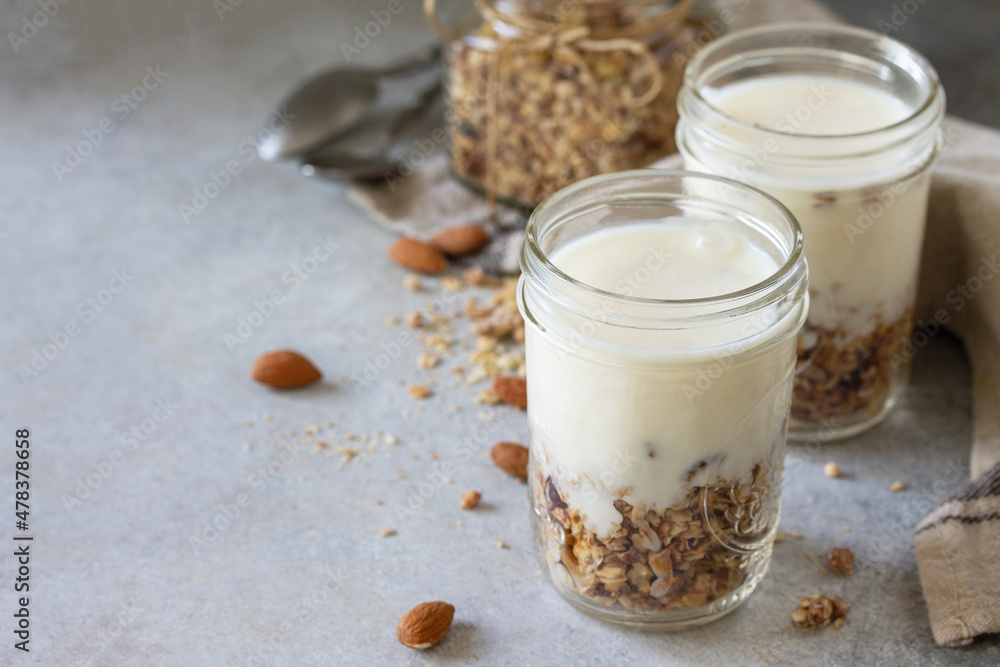 Healthy breakfast, yogurt parfait. Yogurt with homemade almond granola on a gray concrete background. Copy space. Healthy breakfast, yogurt parfait. Yogurt with homemade almond granola on a gray concrete background. Copy space.