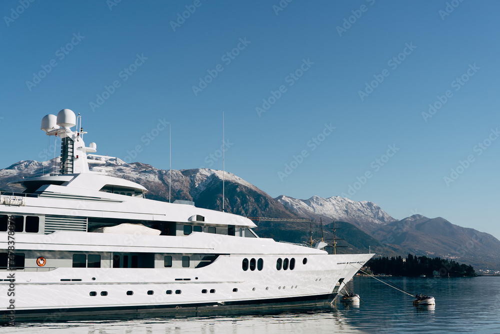 White two-deck yacht moored at the pier with mountains in the background