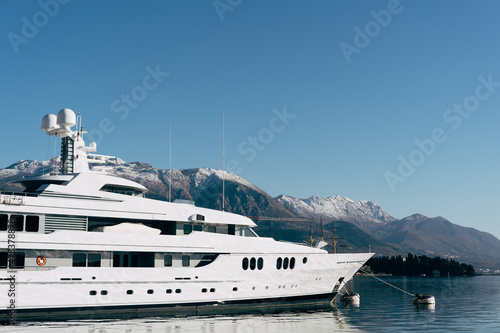 White two-deck yacht moored at the pier with mountains in the background © Nadtochiy