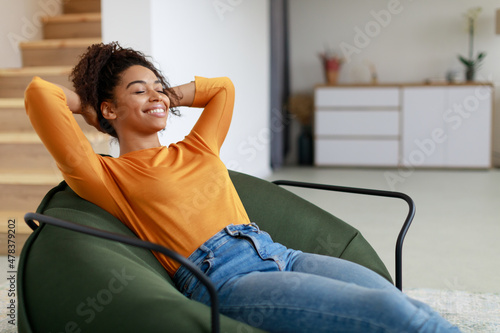 Fotografija Calm black woman having rest at home on the puff